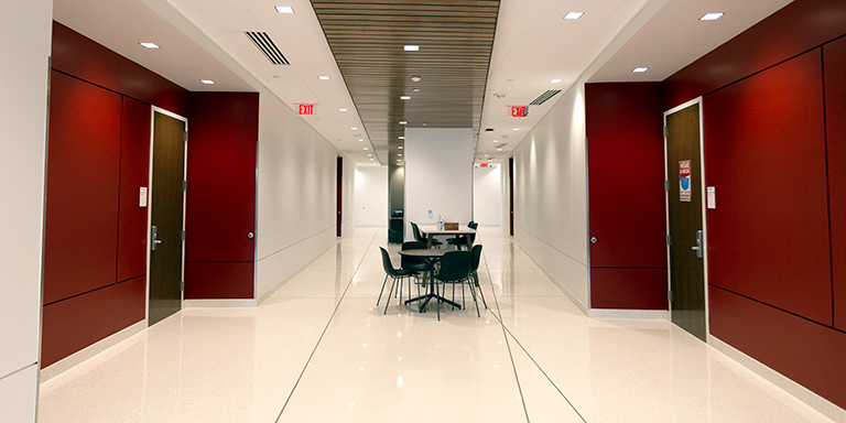 View of a common area with seating and doors to classrooms on the first floor of the health sciences building.