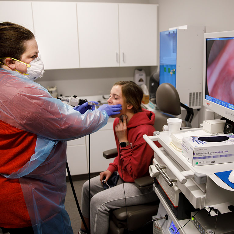 A technician looks at a live image of a patient's vocal cords